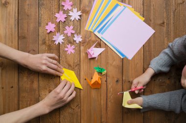 Ebeveyn ve çocuk elleri origami ile oynuyor