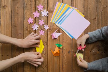 Ebeveyn ve çocuk elleri origami ile oynuyor