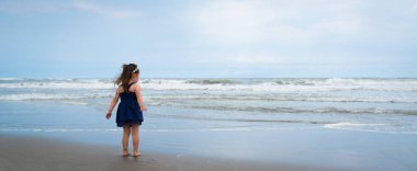 Küçük kız sahilde eğleniyor.