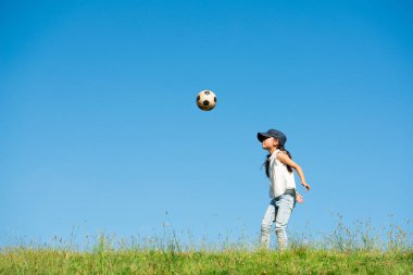 Küçük kız çimenlerde futbol oynuyor. 