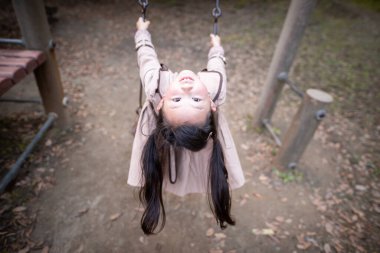 Parkta salıncakta sallanan küçük tatlı Asyalı kız.