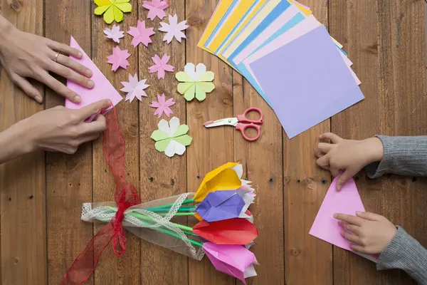 Ebeveyn ve çocuk elleri origami ile oynuyor