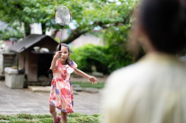 Anne ve kızı yazın badminton oynuyorlar.