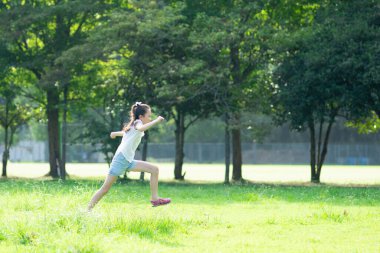Genç Asyalı kız parkta eğleniyor. 
