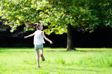 Genç Asyalı kız parkta eğleniyor. 