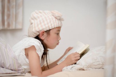 Yatakta kitap okuyan kız.