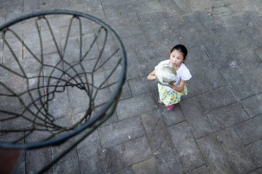 Kız parkta basketbol oynuyor.