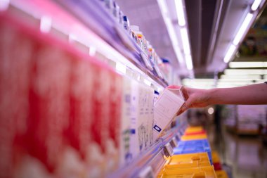 Kadın süpermarketten süt alıyor.