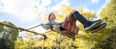 Parkta oyun parkında oynayan küçük tatlı Asyalı kız.