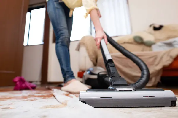 Woman cleaning the room with a vacuum cleaner