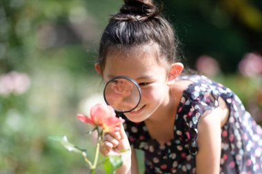 Çiçekteki büyüteçten bakan küçük kızın portresi