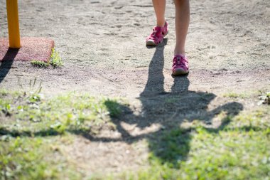 Demir çubuk oynayan bir çocuğun bacakları ve gölgeleri. 