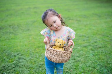 little asian girl with teddy bear  in park.