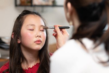 Annesine makyaj yaptıran bir kız.