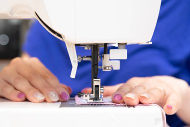 Dikiş makinesi kullanan bir kadının elleri.