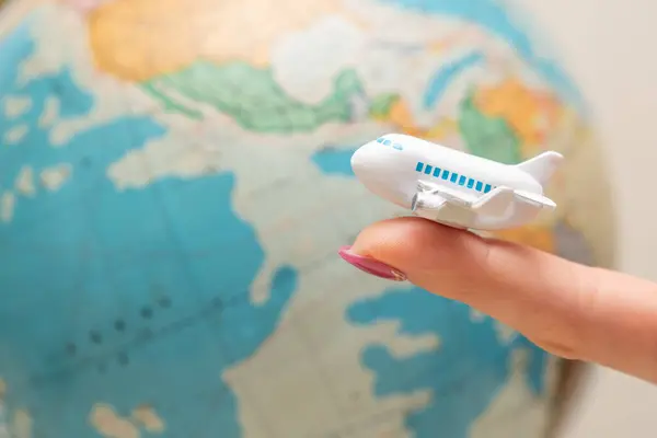 Woman's hand holding toy airplane and world map