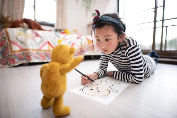 A girl drawing a picture of teddy bear