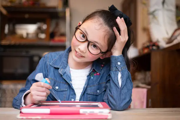 Girl with glasses learning on tablet at home