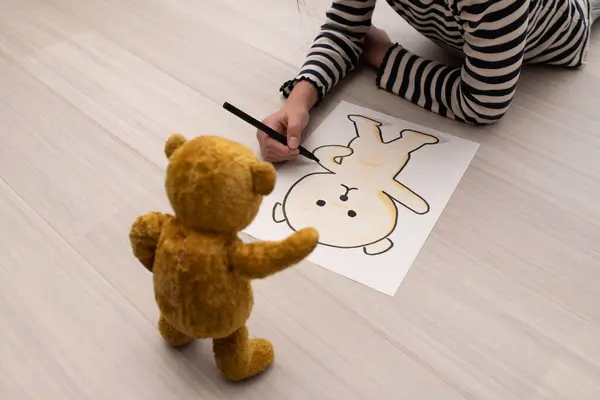 A girl drawing a picture of teddy bear