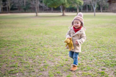 little asian girl with teddy bear  in park.