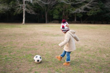 Kız futbol topuyla oynuyor.