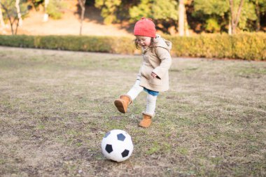 Küçük kız çimenlerde futbol oynuyor. 
