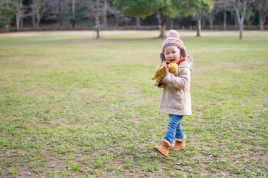 Parkta oyuncak ayıyla oynayan bir kız.