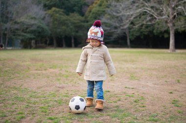 Küçük kız çimenlerde futbol oynuyor. 