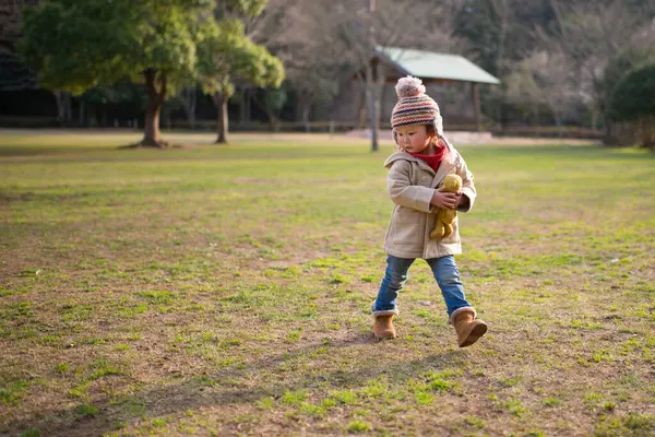 little asian girl with teddy bear  in park.