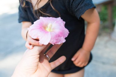 Ebeveyn ve çocuk ellerinde bir çiçek tutuyor.