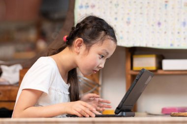 Küçük kız mutfakta dizüstü bilgisayar kullanıyor.