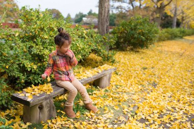 Küçük kız sonbahar parkında bankta