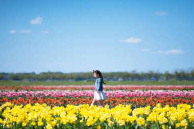 İlkbaharda çiçek tarlalarında küçük sevimli Asyalı kız
