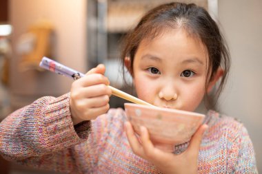 Yemek çubuğuyla pirinç yiyen kız.