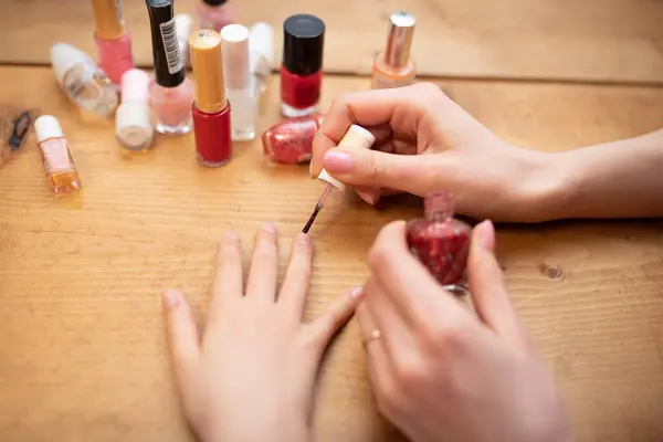 Mother\'s hand applying nail polish to her daughter\'s nails