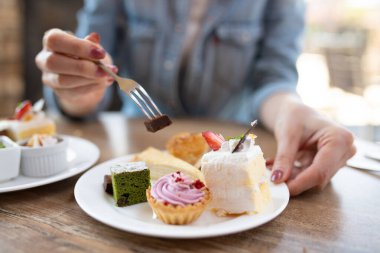 Kafede kek yiyen genç bir kadın.