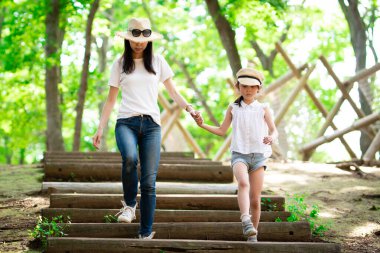 Anne ve kızı orman merdivenlerinde el ele yürüyorlar.