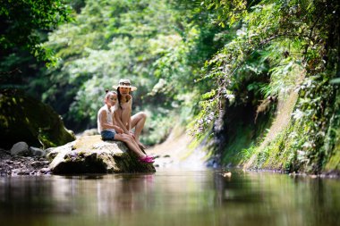 Anne ve kızı dağ deresinde oynuyorlar.