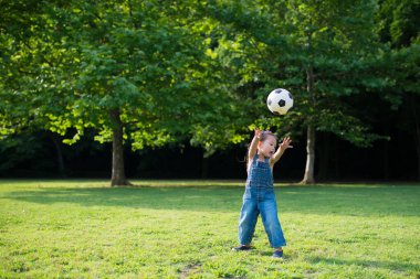 Kız futbol topuyla oynuyor. 