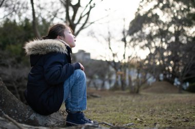 bir ağaç gövdesinde oturan kız