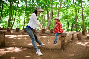 Anne ve kızı orman parkında oynuyor.