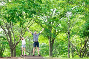 Baba ve kızı ormanda ellerini açıyor.