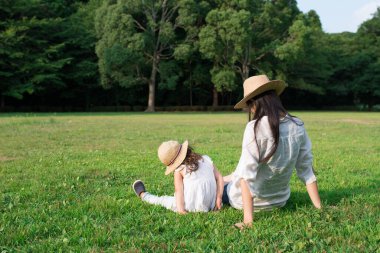 Anne ve kızı çimenlerde oynuyorlar.