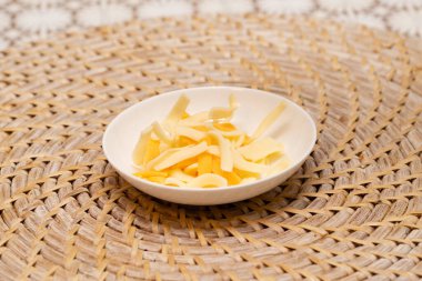 Küçük beyaz tabakta dilimlenmiş peynir.