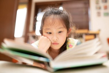 Kız uzanıp kitap okuyor.