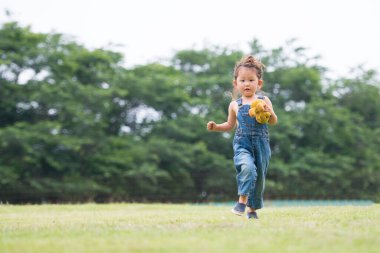 Tulum giymiş oyuncak ayıyla oynayan bir kız. 