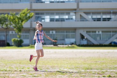 Genç Asyalı kız parkta koşuyor..
