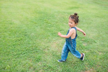 Küçük kız çimlerin üzerinde yürüyor, yaz