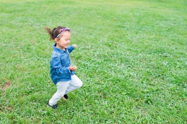 Parkta çimenlerde koşan bir kız