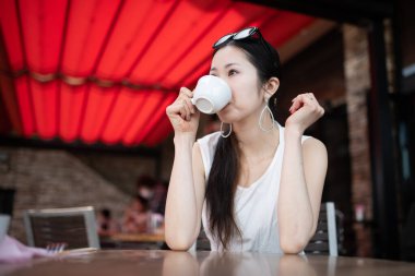 Kafede kahve içen Asyalı genç bir kadın.